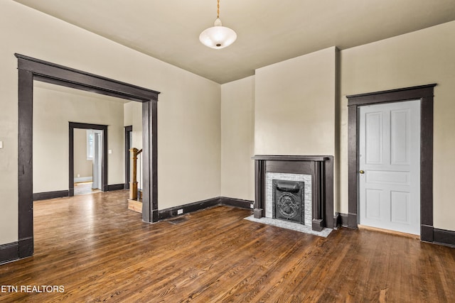 unfurnished living room with baseboards, a fireplace with flush hearth, and wood finished floors