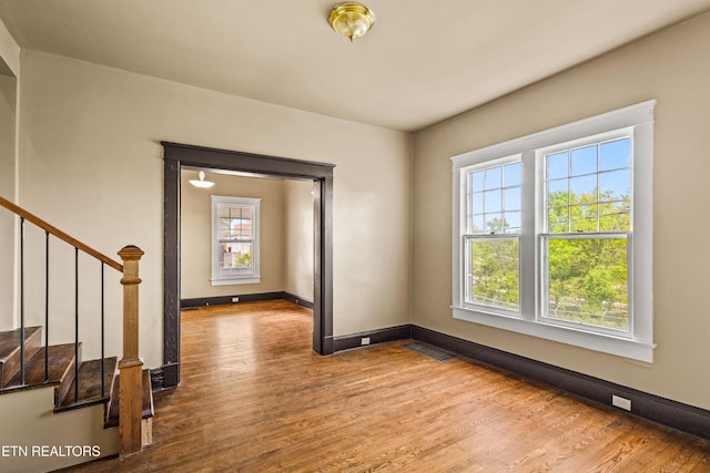 unfurnished room featuring baseboards, stairs, wood finished floors, and visible vents