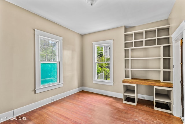 interior space with baseboards, a healthy amount of sunlight, and wood finished floors