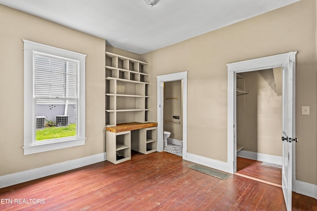 unfurnished bedroom with baseboards, connected bathroom, and wood finished floors