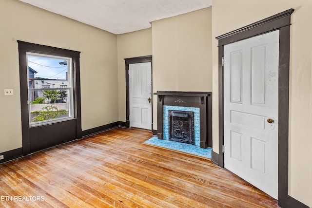 unfurnished living room featuring baseboards, a fireplace with flush hearth, and light wood-type flooring