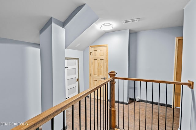 corridor with visible vents, wood finished floors, and an upstairs landing