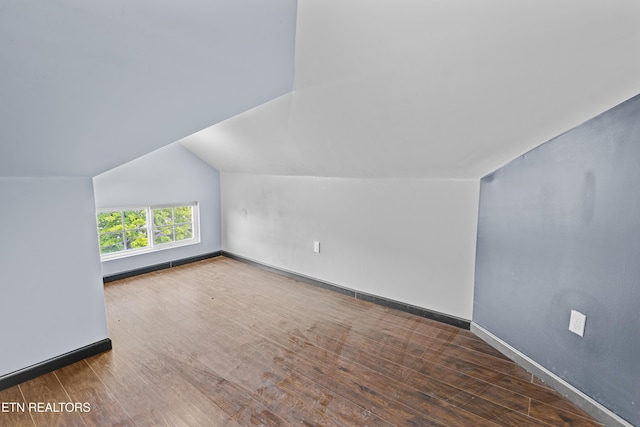 additional living space featuring baseboards, vaulted ceiling, and wood finished floors