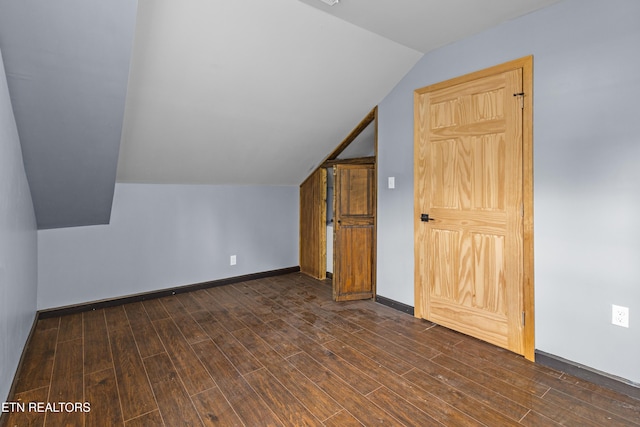 additional living space featuring baseboards, dark wood finished floors, and lofted ceiling