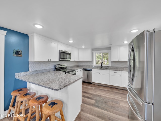 380 Buster Blvd, Lenoir City, TN 37772 - kitchen featuring white cabinets, appliances with stainless steel finishes, a sink, a peninsula, and decorative backsplash