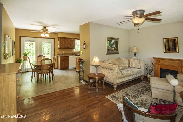 living area featuring ceiling fan, a fireplace, and wood finished floors
