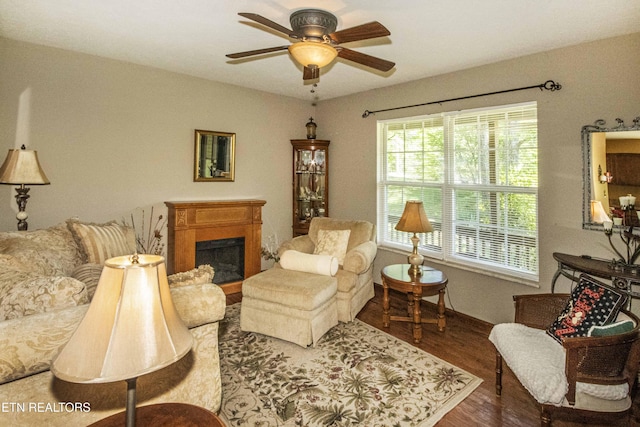 living area featuring ceiling fan, a wealth of natural light, wood finished floors, and a fireplace