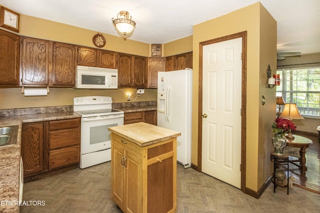 kitchen featuring brown cabinetry, wooden counters, white appliances, ceiling fan, and a center island