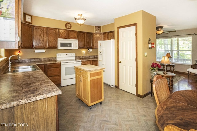 kitchen with a sink, white appliances, a ceiling fan, baseboards, and a kitchen island