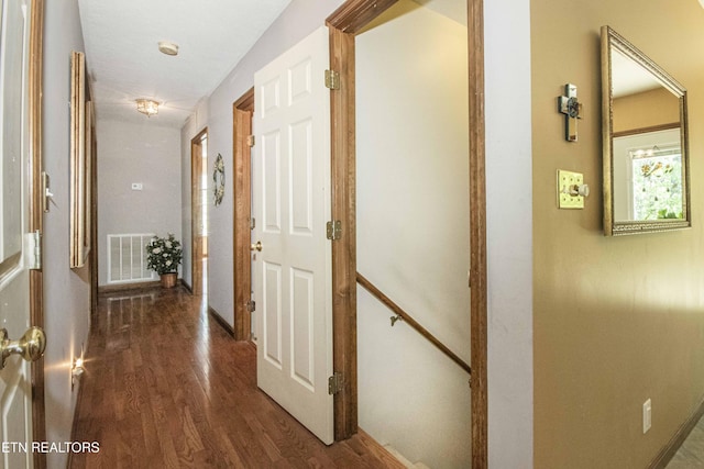hallway featuring visible vents, baseboards, and dark wood-style floors