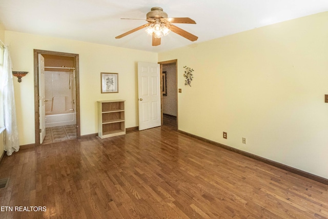unfurnished bedroom featuring a ceiling fan, visible vents, wood finished floors, baseboards, and connected bathroom