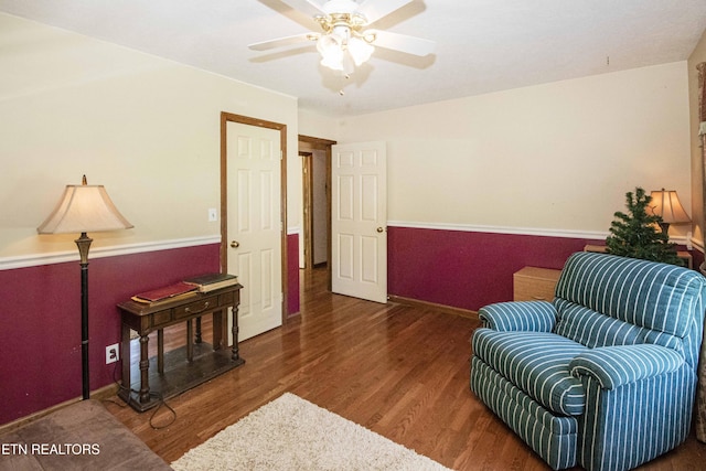 sitting room featuring baseboards, a ceiling fan, and wood finished floors