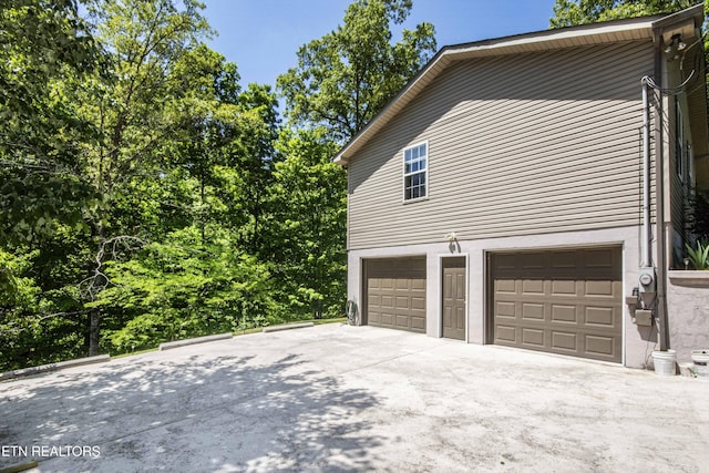 view of property exterior featuring a garage and concrete driveway