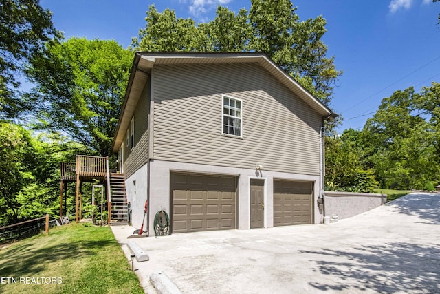 view of side of property featuring a wooden deck, driveway, an attached garage, a yard, and stairway