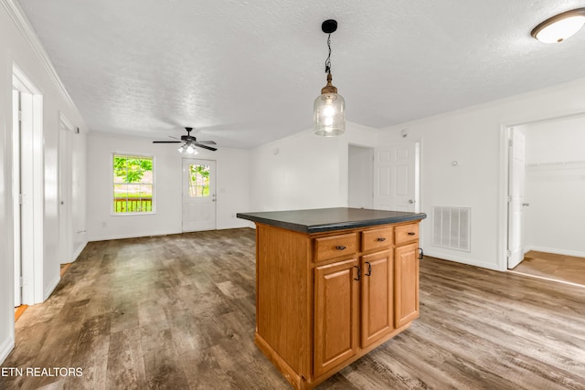 2208 Island Blvd, Sevierville, TN 37876 - kitchen featuring a textured ceiling, wood finished floors, dark countertops, ceiling fan, and a kitchen island