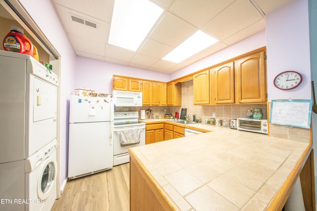 57 Eagle Ct, Crossville, TN 38558 - kitchen with white appliances, estacked washer and dryer, tile countertops, a peninsula, and backsplash