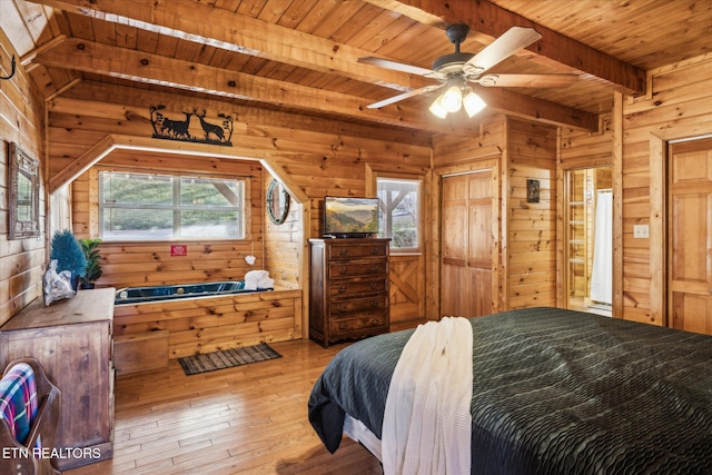bedroom with beamed ceiling, wood walls, multiple windows, and wood ceiling