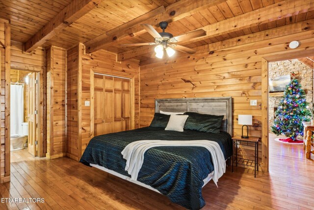 bedroom with wooden walls, beamed ceiling, wood ceiling, and hardwood / wood-style flooring