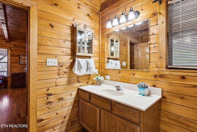bathroom featuring wood-type flooring, wood walls, and vanity
