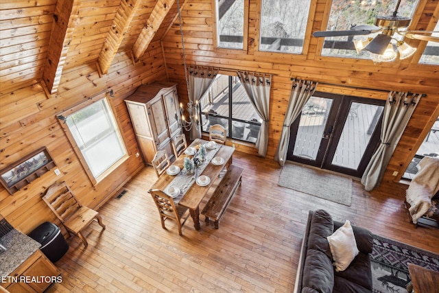 living area featuring wood-type flooring, ceiling fan, and wooden walls