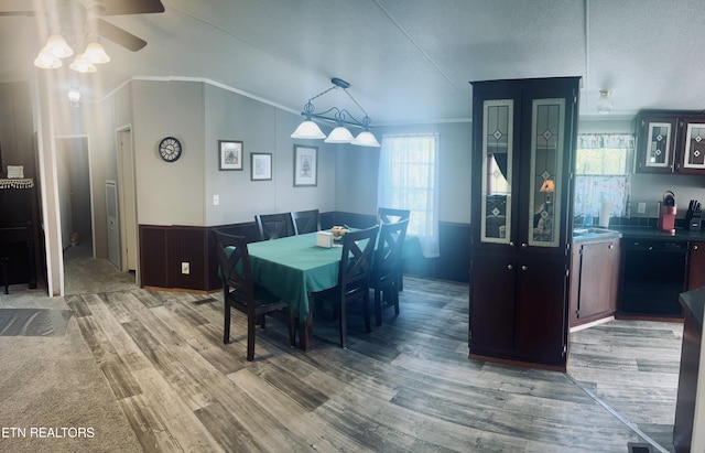 dining room featuring ceiling fan, vaulted ceiling, wainscoting, light wood finished floors, and ornamental molding
