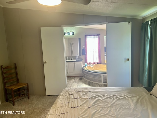 bedroom featuring ensuite bathroom, a sink, vaulted ceiling, and light colored carpet