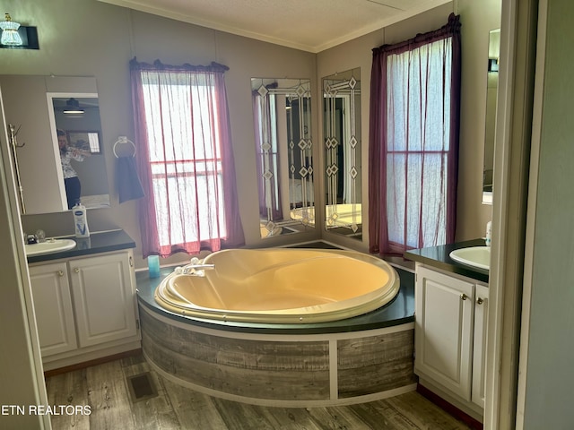 full bath featuring crown molding, a sink, two vanities, and wood finished floors