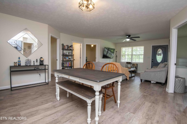 dining area with baseboards, ceiling fan, light wood-style flooring, and a textured ceiling