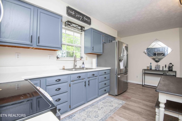 kitchen featuring a sink, light wood-style floors, black electric range, stainless steel fridge with ice dispenser, and blue cabinets