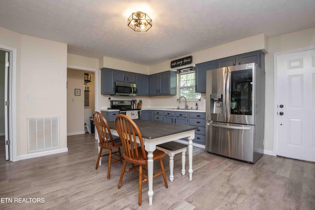 dining area featuring a textured ceiling, visible vents, baseboards, and light wood-type flooring