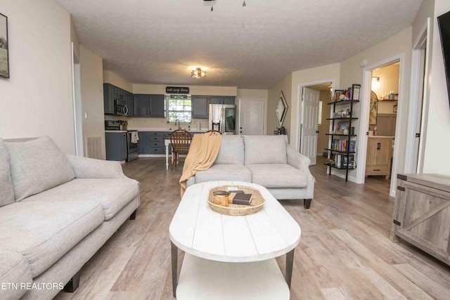 living room with visible vents, a textured ceiling, and light wood-style flooring