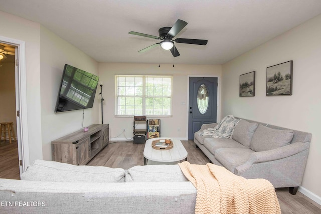living area featuring baseboards, ceiling fan, and wood finished floors