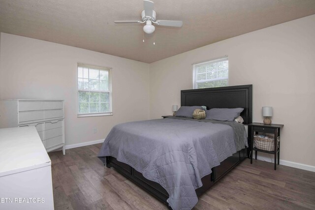 bedroom with baseboards, multiple windows, and wood finished floors
