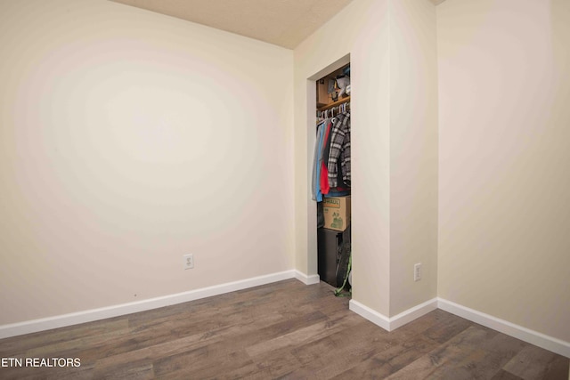 unfurnished bedroom with baseboards, dark wood finished floors, and a closet