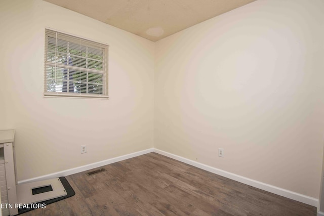 empty room featuring baseboards, wood finished floors, and visible vents