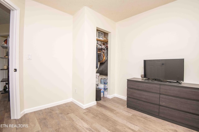 unfurnished bedroom with a walk in closet, baseboards, light wood-style flooring, and a closet