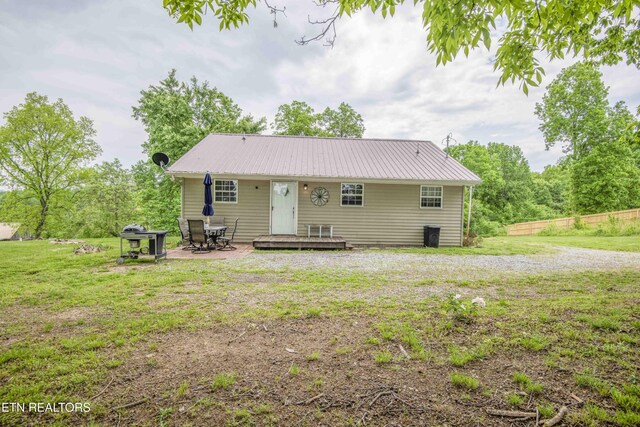 back of property with fence, a wooden deck, a yard, and metal roof
