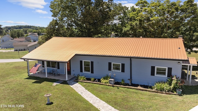 view of front of home with covered porch, metal roof, and a front yard