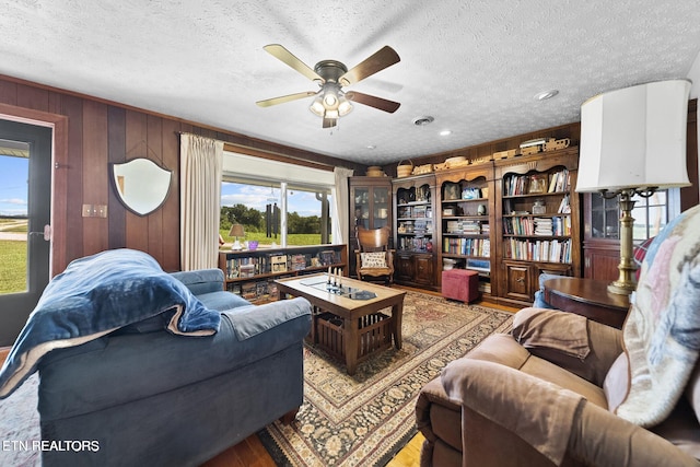 living area with light wood finished floors, a textured ceiling, wood walls, a ceiling fan, and recessed lighting