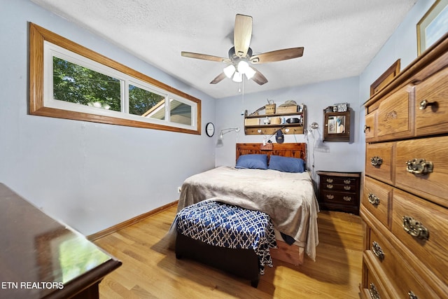 bedroom featuring light wood-type flooring, a ceiling fan, a textured ceiling, and baseboards