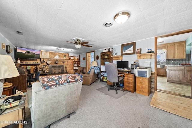 office area featuring ceiling fan, a fireplace, carpet flooring, and visible vents