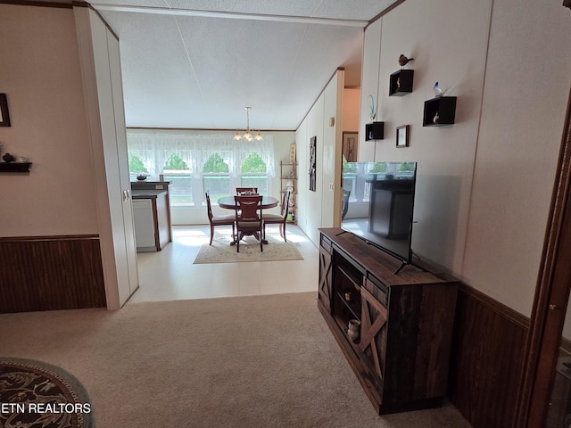 hall with wooden walls, tile patterned floors, an inviting chandelier, and wainscoting