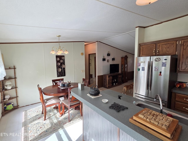 kitchen featuring an inviting chandelier, freestanding refrigerator, lofted ceiling, and decorative light fixtures