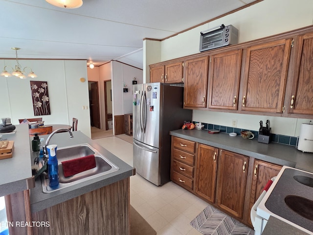 kitchen with brown cabinetry, a sink, dark countertops, and freestanding refrigerator