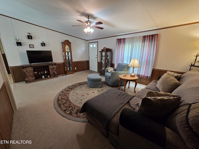 carpeted living room featuring wooden walls, ceiling fan, a wainscoted wall, and vaulted ceiling