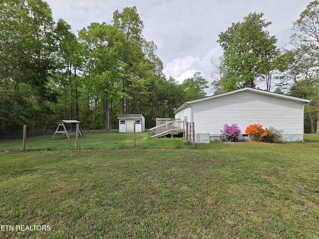 view of yard featuring a wooden deck, fence, an outdoor structure, and a shed