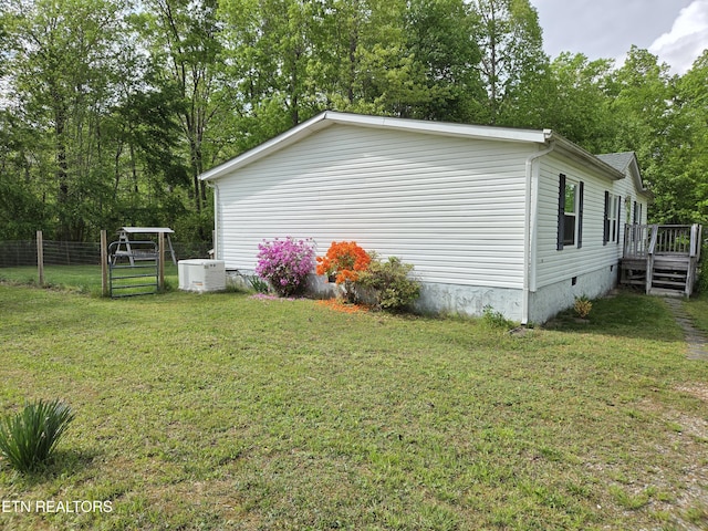 view of side of property with a lawn, crawl space, fence, and a deck