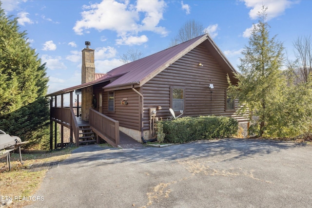 view of side of home featuring a chimney and metal roof