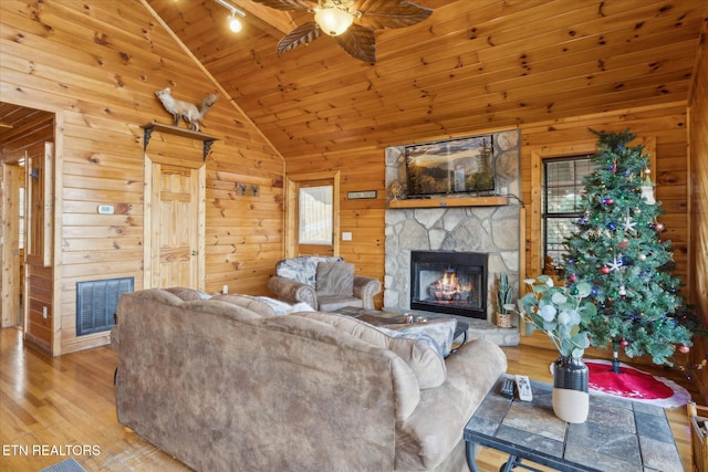 living room with visible vents, wood finished floors, vaulted ceiling, and a fireplace