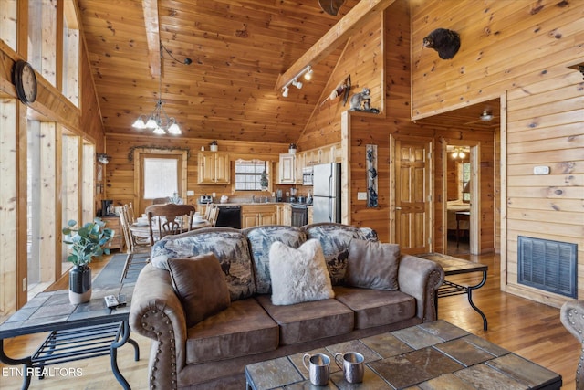 living room featuring wood ceiling, rail lighting, high vaulted ceiling, a chandelier, and wooden walls